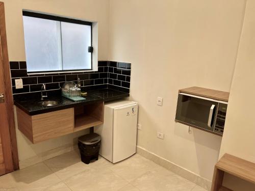 uma pequena cozinha com um lavatório e um frigorífico em Marmeu Tombo no Guarujá