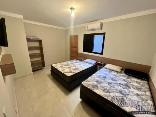 1 dormitorio con 2 camas y TV en la pared en Marmeu Tombo, en Guarujá