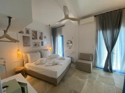 ein weißes Schlafzimmer mit einem Bett und einem Stuhl in der Unterkunft Kores of Poros in Poros