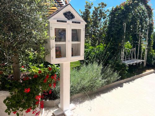 a white bird house in a garden with flowers at Casa di Fiore SPA and Medical Hotel, Mineral Pools & Private Beach in Kranevo