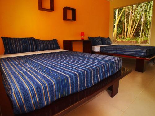 1 dormitorio con 2 camas y ventana en Hotel Colores del Arenal, en Fortuna