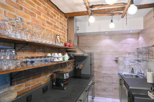 Klecherova House في بانسكو: مطبخ بحائط من الطوب مع كاسات على الرفوف
