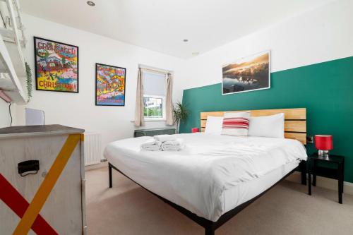 a bedroom with a large bed with a green wall at GuestReady - Artsy Penthouse in Heart of the City in London