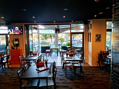 uma sala de jantar com mesas e cadeiras num restaurante em Qure Restaurant and Apartments Canberra Bruce em Canberra