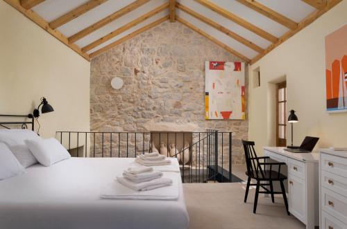 a bedroom with a white bed and a stone wall at Dvor Pitve Villas in Jelsa