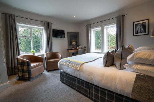 a bedroom with a bed and a chair and windows at The Inn South Stainley in Harrogate