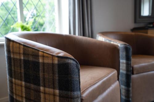 two brown leather chairs sitting next to a window at The Inn South Stainley in Harrogate