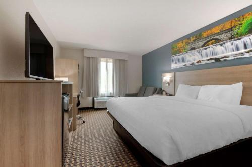 a hotel room with a bed and a flat screen tv at Clarion Pointe Tomah in Tomah