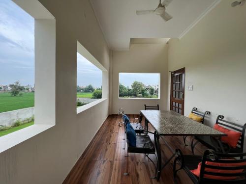 uma sala de jantar com uma mesa e duas janelas em Param Country Home With Pool em Jalandhar