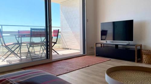 a living room with a flat screen tv and a balcony at Large studio direct access to the beach in Pornichet