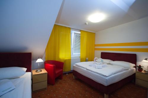 um quarto de hotel com duas camas e uma cadeira vermelha em Hotel City Residence em Viena