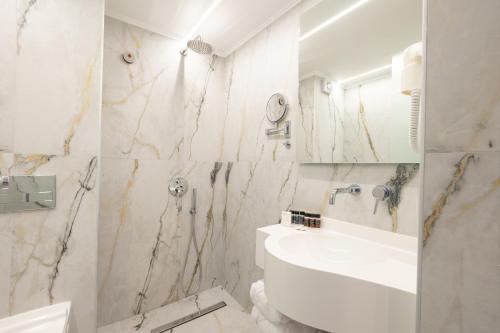 a white bathroom with a sink and a mirror at Modern Revival Luxury Hotel in Thessaloniki