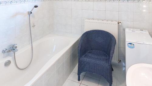 uma casa de banho com uma cadeira azul ao lado de uma banheira em Malerisches Bauernhaus em Lieserhofen