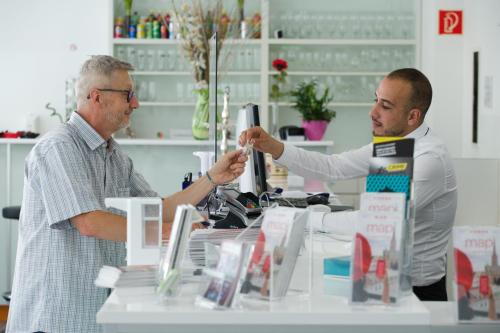 two men standing at a counter in a store at Hotel City Residence in Vienna
