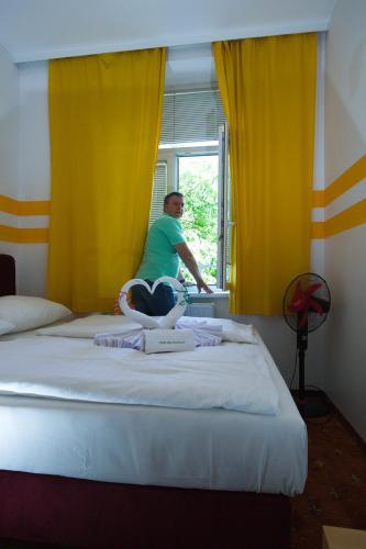 a man sitting on a bed looking out the window at Hotel City Residence in Vienna