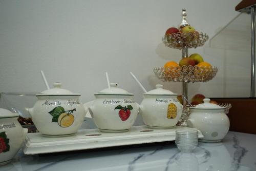 a table with four tea pots and a bowl of fruit at Hotel City Residence in Vienna