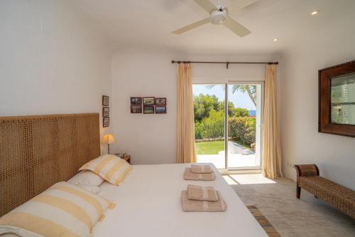 a bedroom with a bed with a ceiling fan and a window at EL PORTET - Managed by Almarina Villas in Benissa