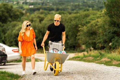 a man and woman walking down a road with a cart at Oaklane Glamping Cabins in Kenmare