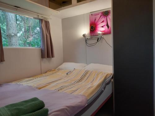 a bed in a room with a flower on the wall at Domek holenderski w Stadnine Koni Mazury in Łukta