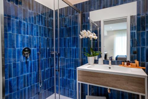 ein blau gefliestes Bad mit einem Waschbecken und einer Dusche in der Unterkunft Dreamers' Rooms Sorrento in Sorrent