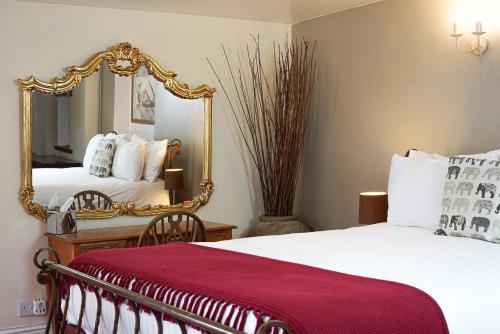 Habitación de hotel con 2 camas y espejo en The Kings Arms Inn, en Oakham