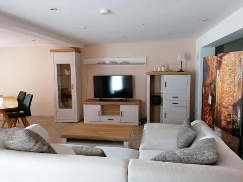 uma sala de estar com 2 sofás brancos e uma televisão de ecrã plano em Casa Mediteran NEU em Reichensachsen