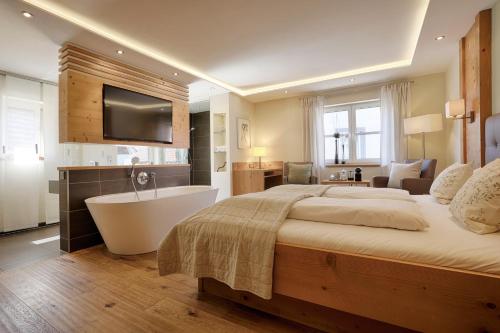 a bedroom with a large bed and a bath tub at Landhotel Schwab - by homekeepers in Schwarzach am Main