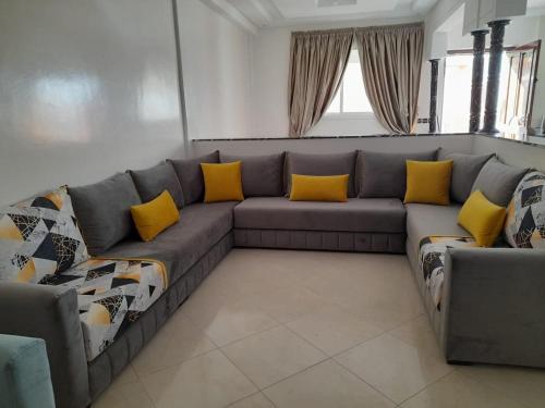 a living room with a gray couch with yellow pillows at Amam's Home in Agadir
