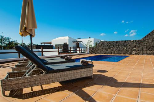 um pátio com um guarda-sol e uma piscina em Villa DaVinci - Playa Blanca em Playa Blanca