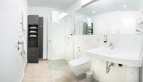 ein weißes Bad mit einem Waschbecken und einem WC in der Unterkunft Das ELB Boardinghouse Hotel Restaurant in Magdeburg
