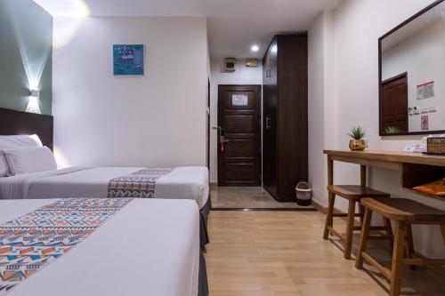 a hotel room with two beds and a desk at 24@Home Hotel in Nonthaburi