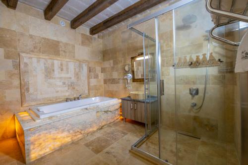 a bathroom with a tub and a glass shower at Underground Cave Suites Hotel in Goreme
