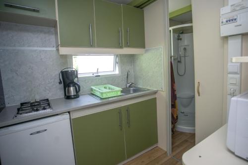 a small kitchen with green cabinets and a sink at Camping Village L'Apamée in Pamiers