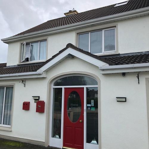 a white house with a red door and windows at Abacus Guesthouse in Galway