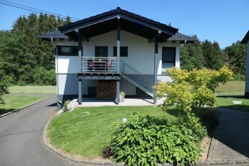 a white house with a porch and a balcony at FEWO Hof Elbbachtal in Westerburg