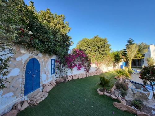 a garden with a blue door on a wall at Au jardin d’Aghir: Villa arborée, avec piscine privée sans vis à vis! in Aghīr