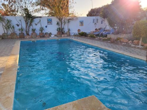 a swimming pool with blue water in a yard at Au jardin d’Aghir: Villa arborée, avec piscine privée sans vis à vis! in Aghīr