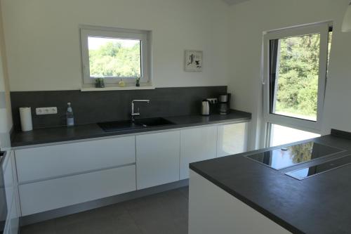 a kitchen with white cabinets and a sink and a window at FEWO Hof Elbbachtal in Westerburg