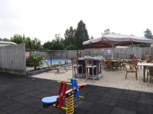 a backyard with a playground with tables and a pool at Chalet Esdoorn in Putten, Gezellig en Luxe gerenoveerd in Putten