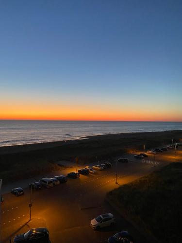 a parking lot with cars parked next to the ocean at Atlantis Appartement in Egmond aan Zee