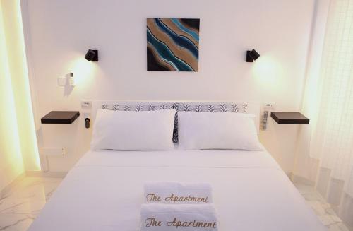 1 dormitorio con 1 cama blanca y una pintura en la pared en The Apartment, en Porto Santo Stefano