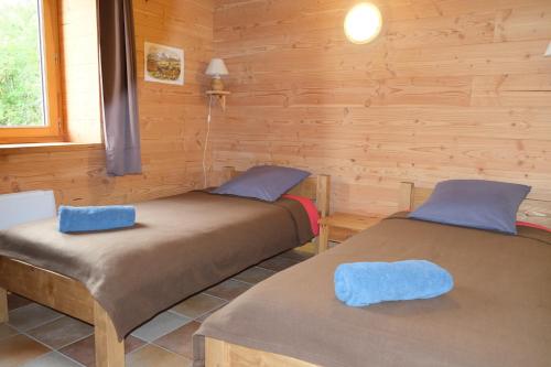 two beds in a room with wooden walls at Gîte Le Corral in Cheminas