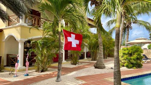 a flag in front of a house with palm trees at Sonrisa Boutique Hotel in Kralendijk