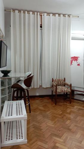 uma sala de estar com pisos em madeira e cortinas brancas em #Apartamento aconchegante no Flamengo - RIO no Rio de Janeiro