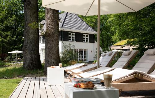 a wooden deck with a table and an umbrella at Relais & Chateaux De Struyckenbergen - villa met wellness in Elspeet