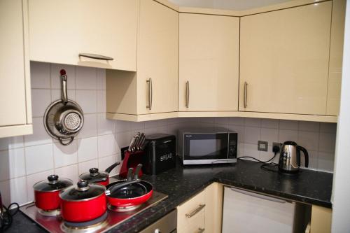 a kitchen with white cabinets and red pots and pans at Stunning Modern Coventry City Apartment Free WiFi in Coventry