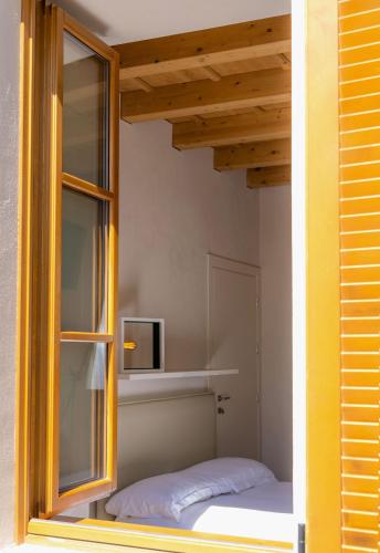 a small bedroom with a bed and a window at Locanda Alberti in Mandello del Lario