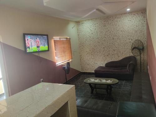 een woonkamer met een bank en een tv aan de muur bij Marigold Hotel in Abuja