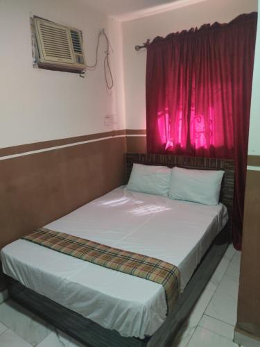 two beds in a room with a red window at Marigold Hotel in Abuja