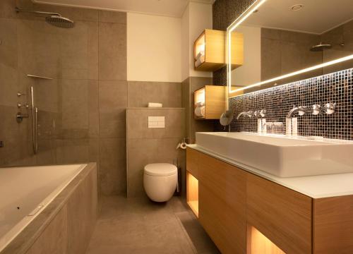 a bathroom with a sink and a toilet and a tub at Relais & Chateaux Hotel Landgoed Het Roode Koper in Ermelo